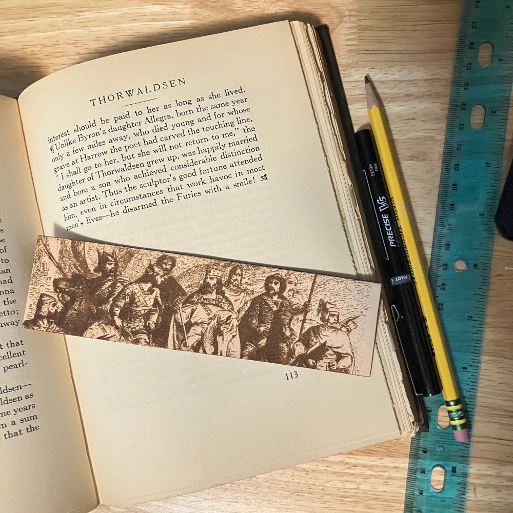 A leather bookmark with the art of a king and his knights on horse back. It might be art of King Aurther Pendragon..