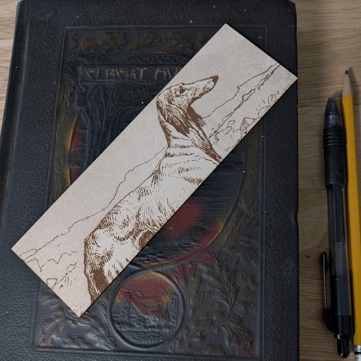 A rectangular leather bookmark with the historical art of an Afghan Greyhound dog engraved on it. Leather Afghan Greyhound Bookmark Bookmarks Raven King Crafts Leather Afghan Greyhound Bookmark Bookmarks Raven King Crafts