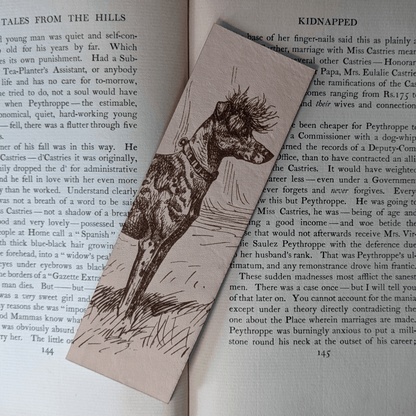 A rectangular leather bookmark with the historical art of a Chinese Crested dog engraved on it. The bookmark is resting on the pages of an open book. Leather Chinese Crested Dog Bookmark Bookmarks Raven King Crafts Leather Chinese Crested Dog Bookmark Bookmarks Raven King Crafts