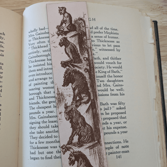 A leather bookmark engraved with the historical art of a collection of gargoyles. Leather Engraved Gargoyles Bookmark