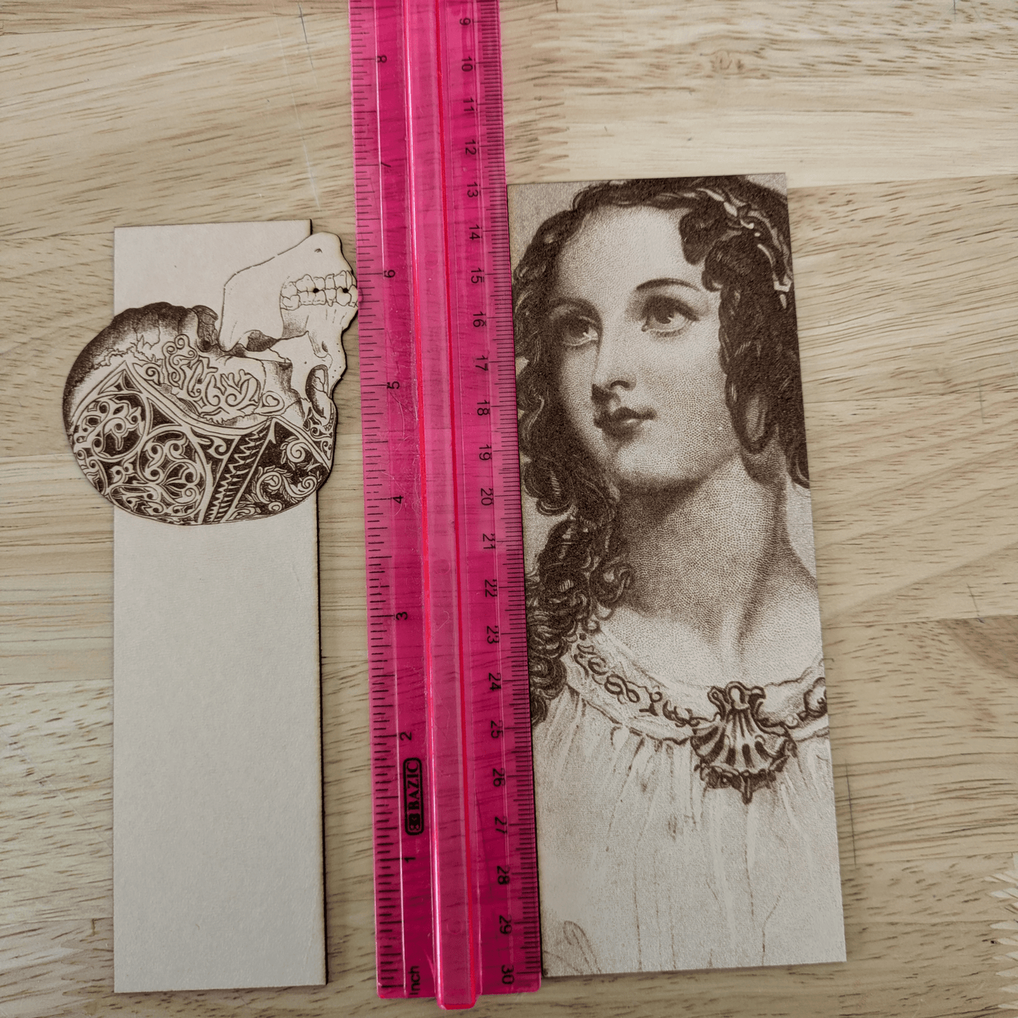 A photograph of a skull bookmark and a woman bookmark next to a ruler. Leather Engraved Skull Bookmark Bookmarks Raven King Crafts
