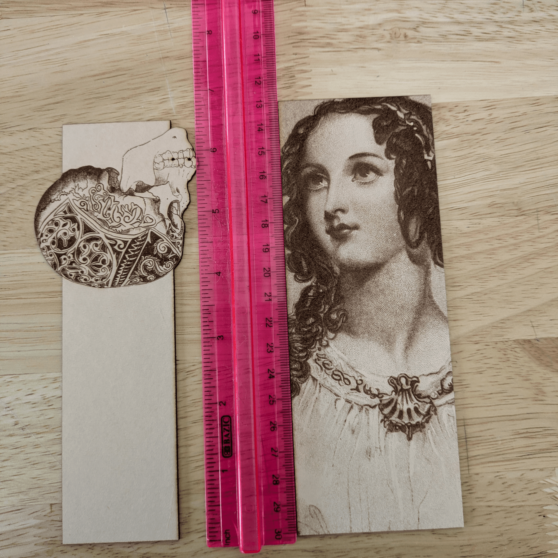 A photograph of a skull bookmark and a woman bookmark next to a ruler. Leather Engraved Skull Bookmark Bookmarks Raven King Crafts