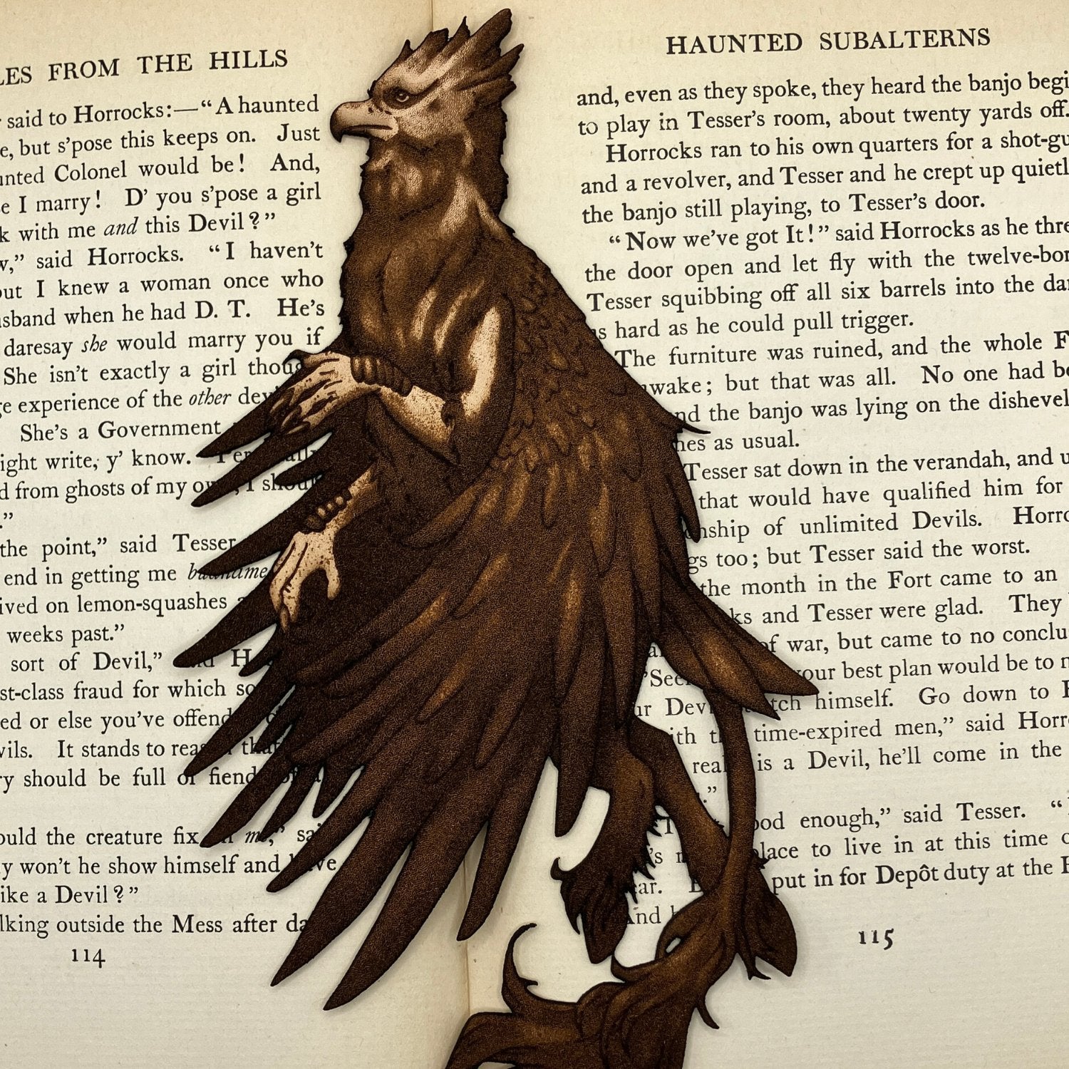 A leather hippogriff bookmark resting on the pages of a book.