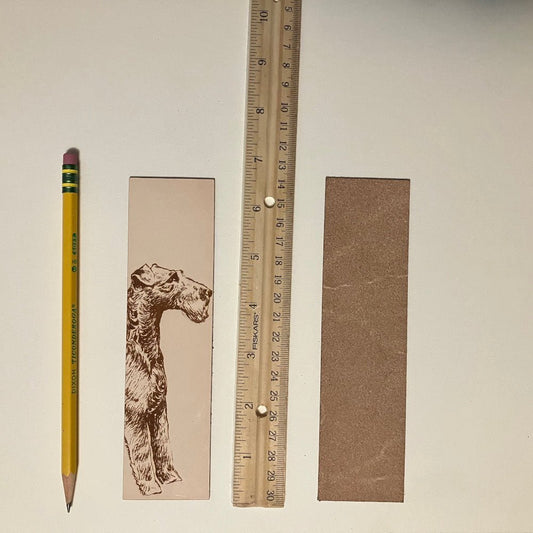 The leather Irish Terrier bookmark next to a ruler and a pencil to show scale. Also the back of the bookmark is unfinished. Leather Irish Terrier Bookmark Bookmarks Raven King Crafts Leather Irish Terrier Bookmark Bookmarks Raven King Crafts