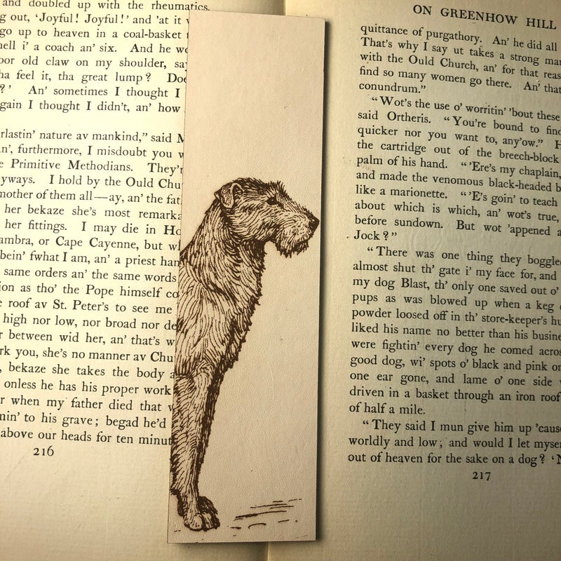 The leather irish wolfhound bookmark resting on the pages of an open book. The book's text is visible around the bookmark.