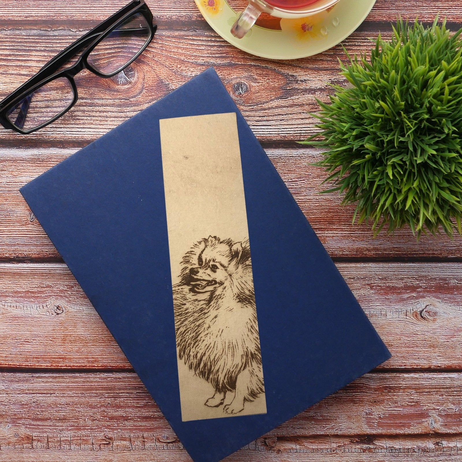 A pom bookmark sitting on top of a book with a blue cover.