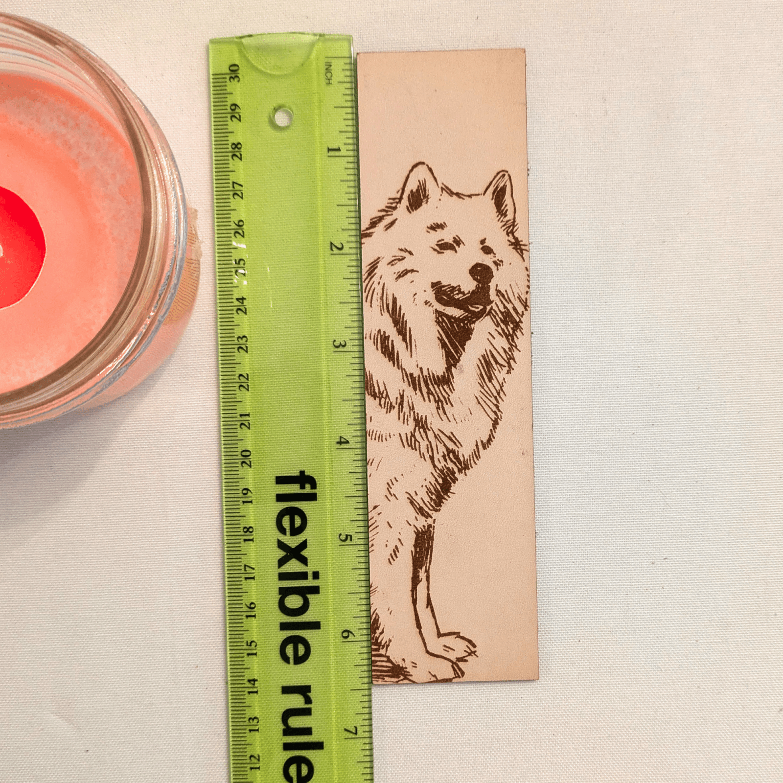 The leather Samoyed, dog bookmark next to a green ruler to show scale. Leather Samoyed Bookmark (working dog) Bookmarks Raven King Crafts Leather Samoyed Bookmark (working dog) Bookmarks Raven King Crafts