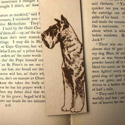 A zoomed in photograph of the schnauzer dog bookmark. It is resting on the pages of an antique book.