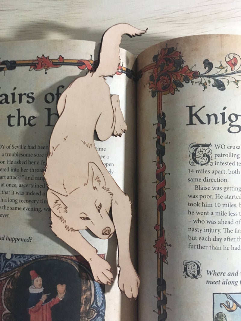 The leather wolf shaped bookmark resting on a book.