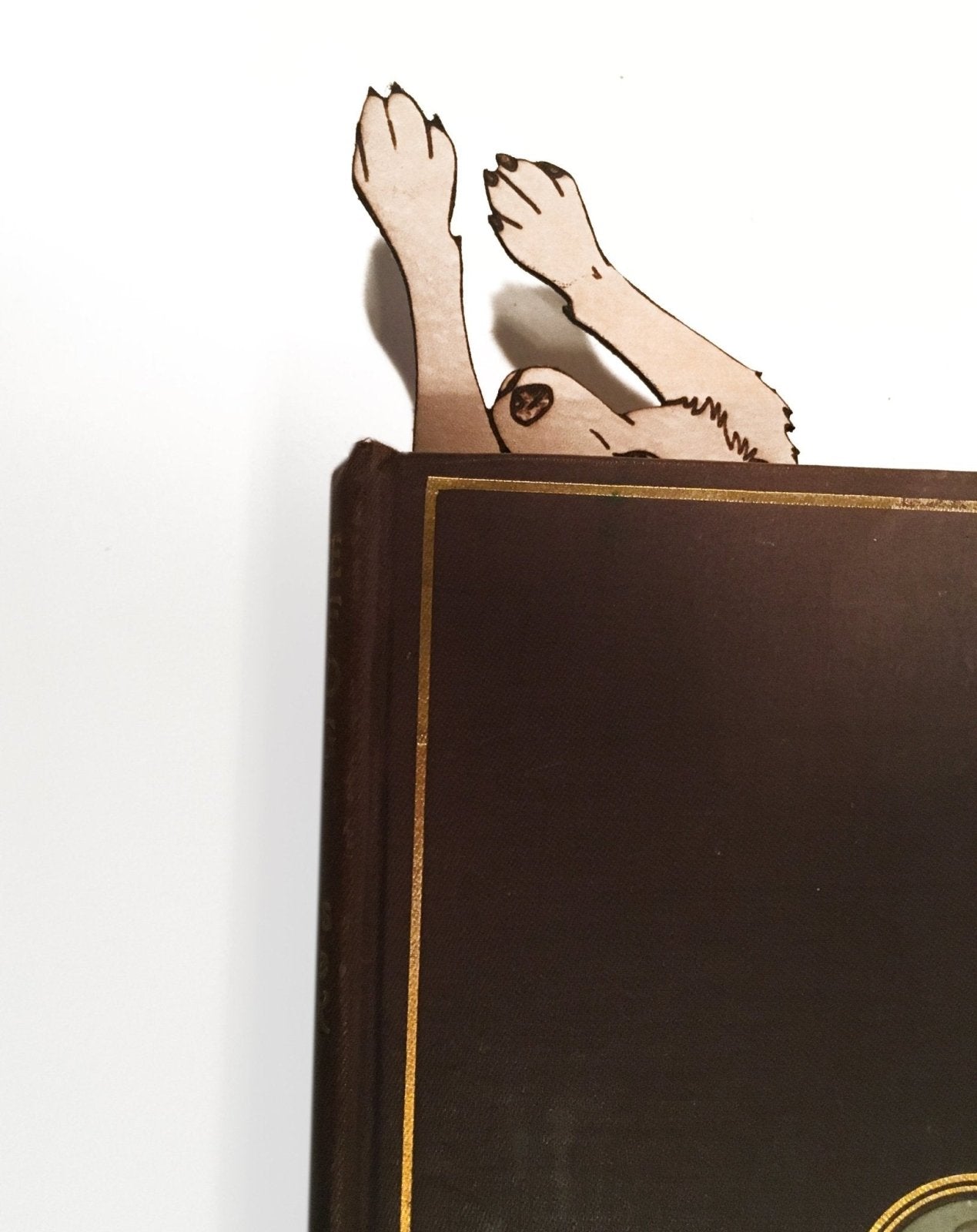 The leather wolf shaped bookmark sticking out of a book.