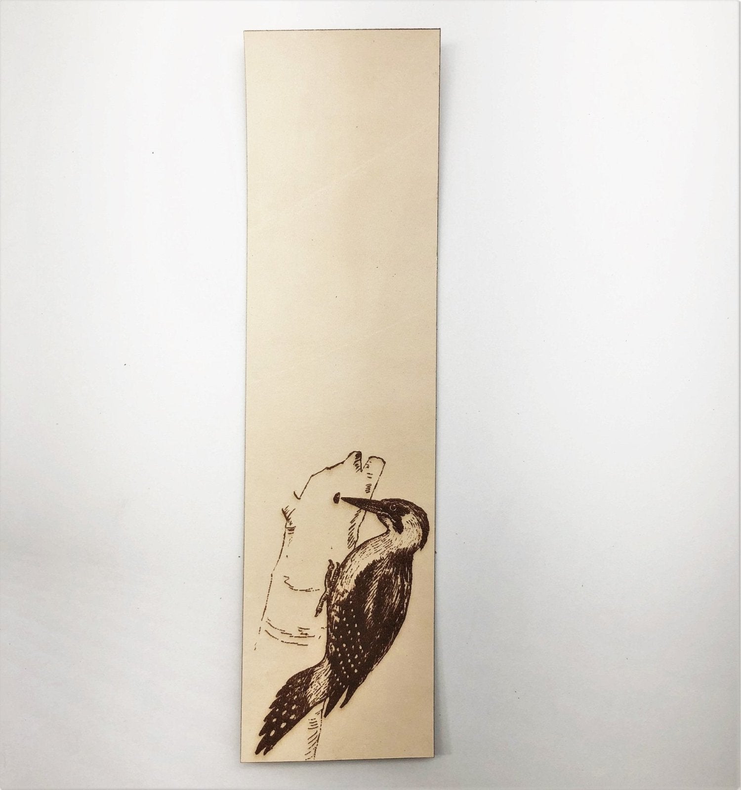 A leather bookmark with the art of a woodpecker engraved on it.