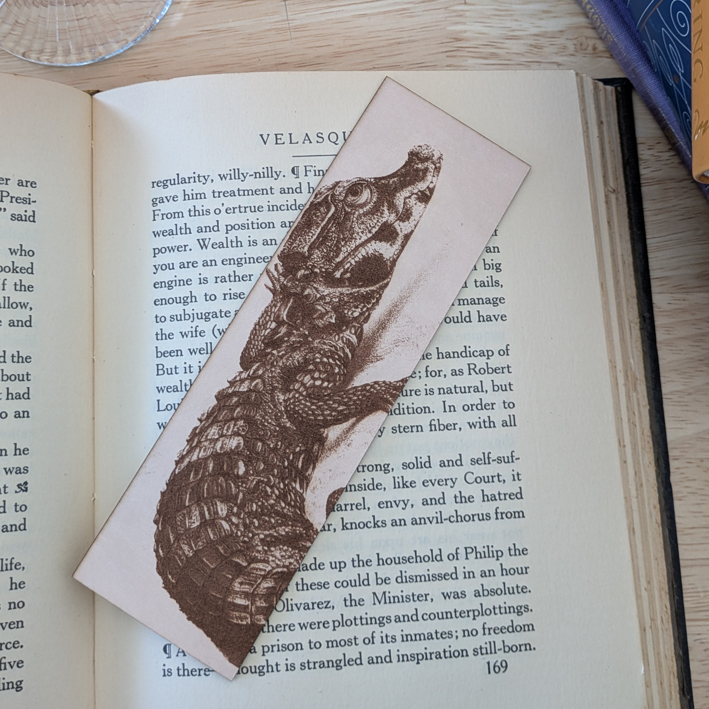 A leather bookmark engraved with the art of a dwarf crocodile engraved on it.