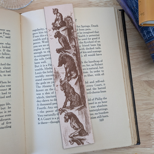 A leather bookmark engraved with the historical art of a collection of gargoyles. 