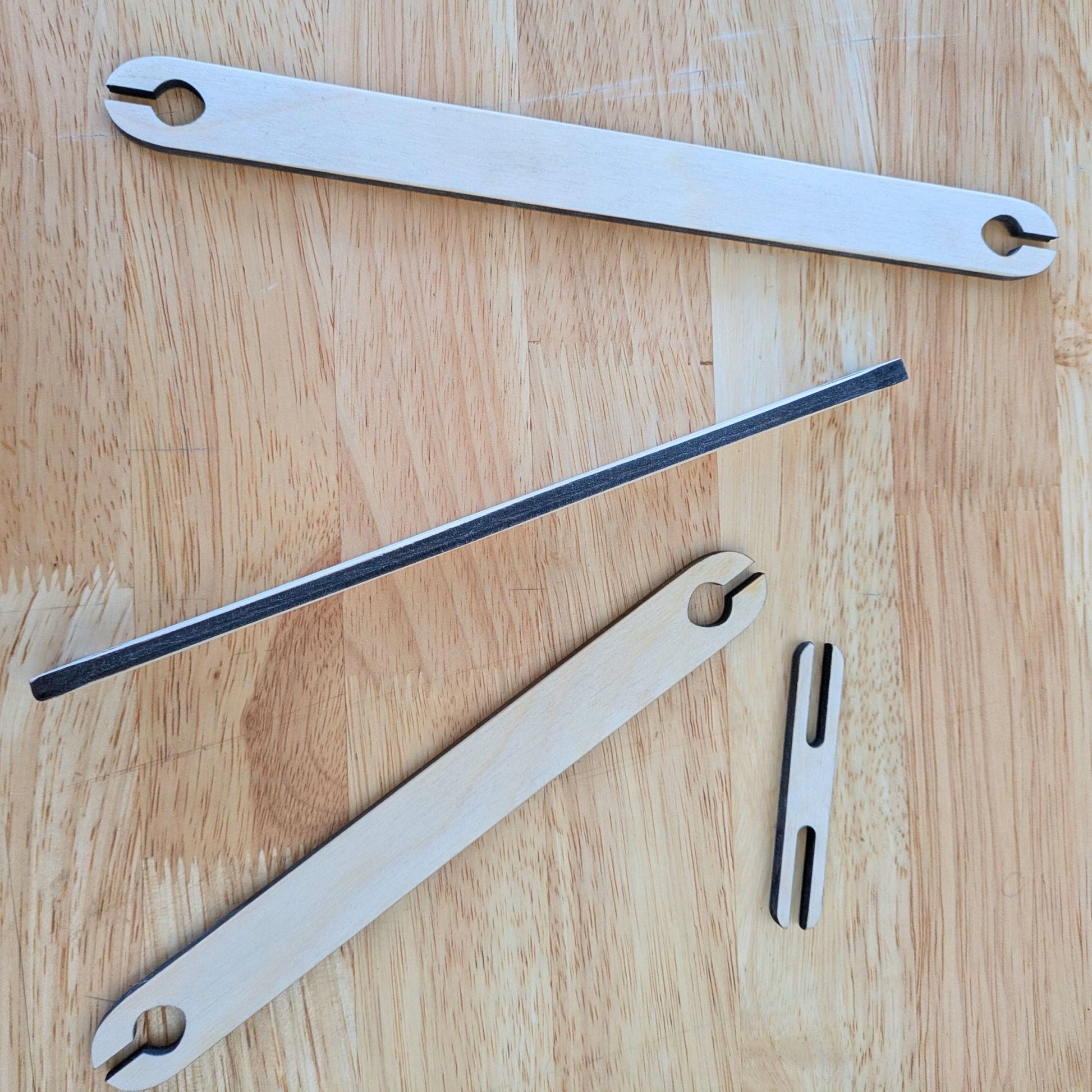 4 wooden shuttle sticks for weaving, one on its side to show the thickness. 