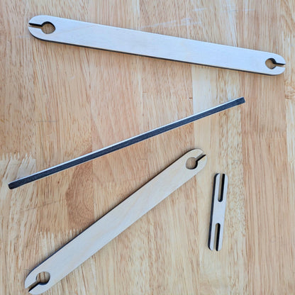 4 wooden shuttle sticks for weaving, one on its side to show the thickness. 