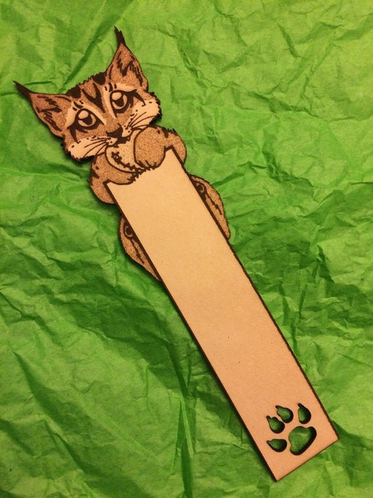 A leather bookmark with a lynx cub holding a heart. At the bottom is a paw print cut out.