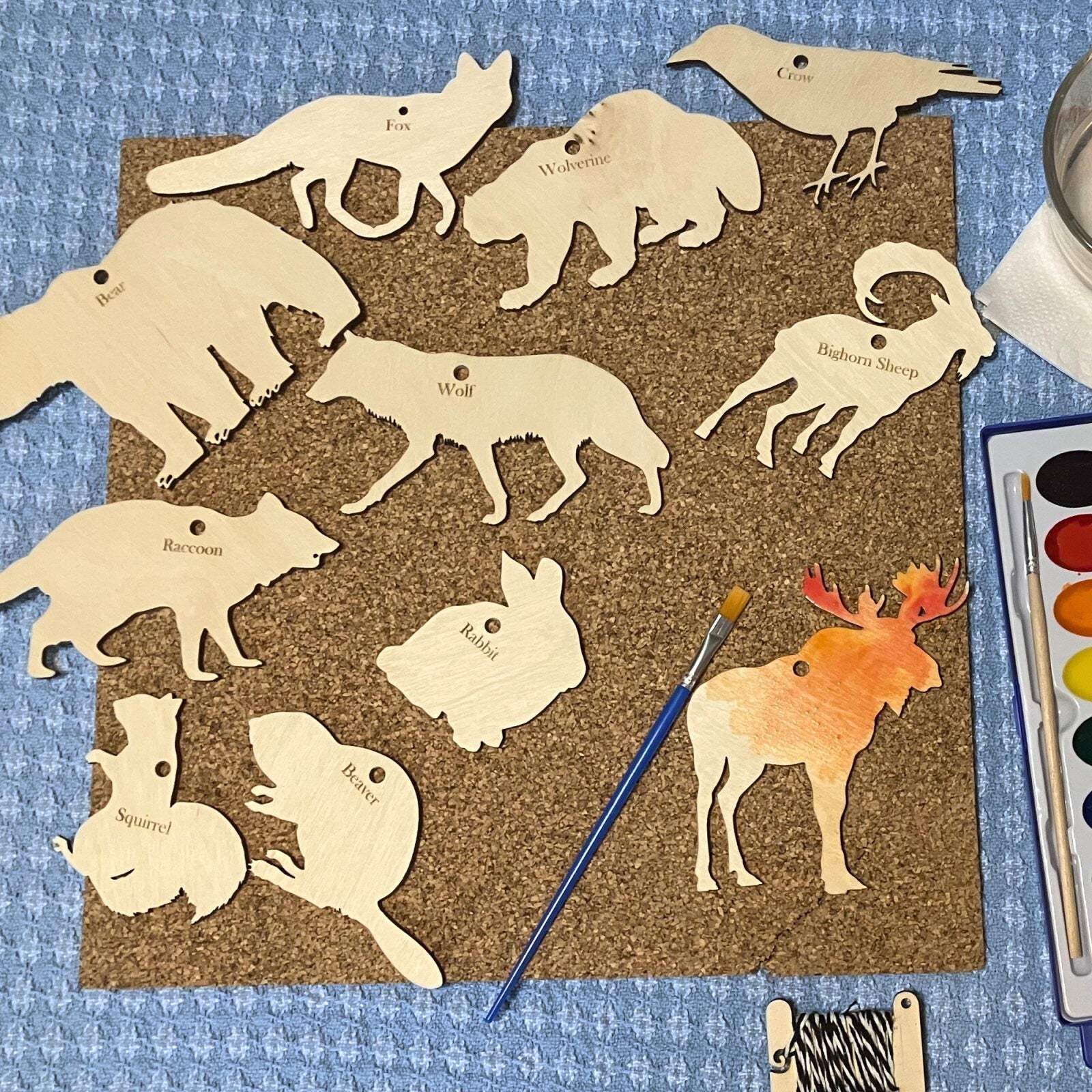 A collection of wood animal cutouts. The moose is being painted with watercolors. North America Wildlife Ornament (Cutout) Kit Art & Craft Kits Raven King Crafts