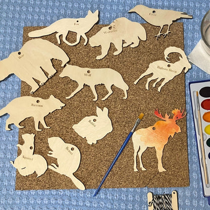 A collection of wood animal cutouts. The moose is being painted with watercolors. North America Wildlife Ornament (Cutout) Kit Art & Craft Kits Raven King Crafts