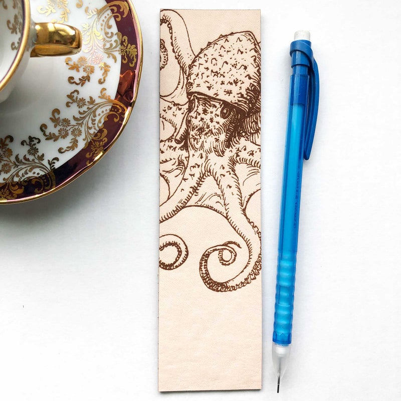 The octopus bookmark next to a mechanical pencil and a tea cup with saucer.