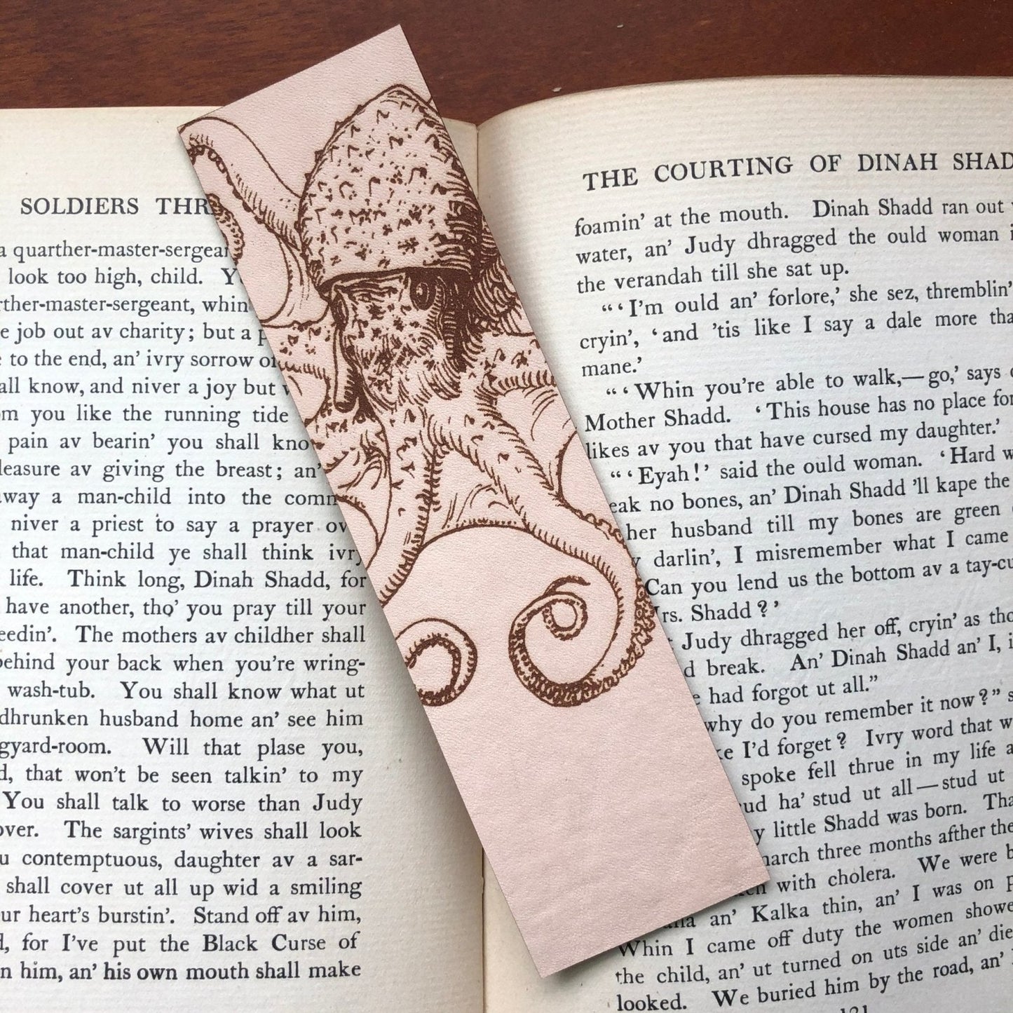 A rectangular leather bookmark with the art of an octopus engraved on it.