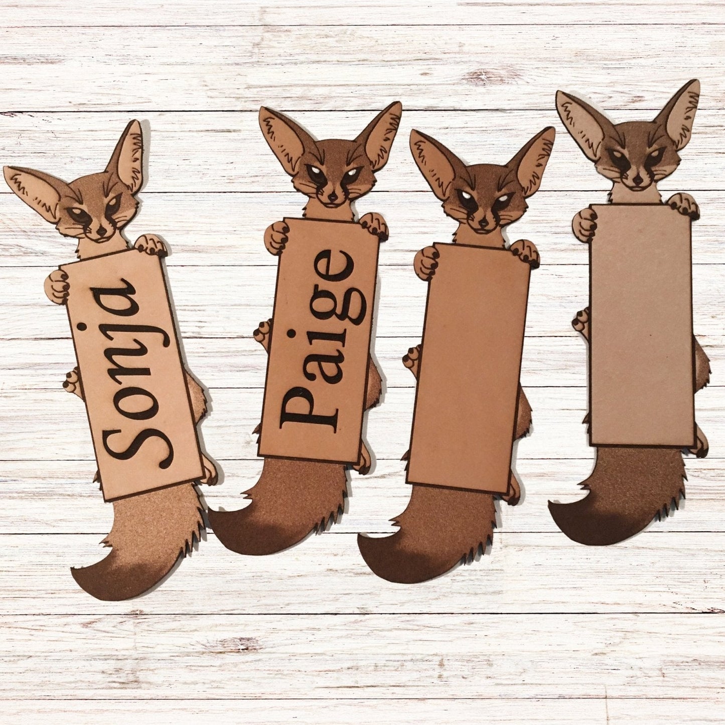 A photo of 4 fennec fox bookmarks. Furthest left is personalized, next is a personalized with white highlights, then just the white highlights and the furthest right is no personalization and no highlights.