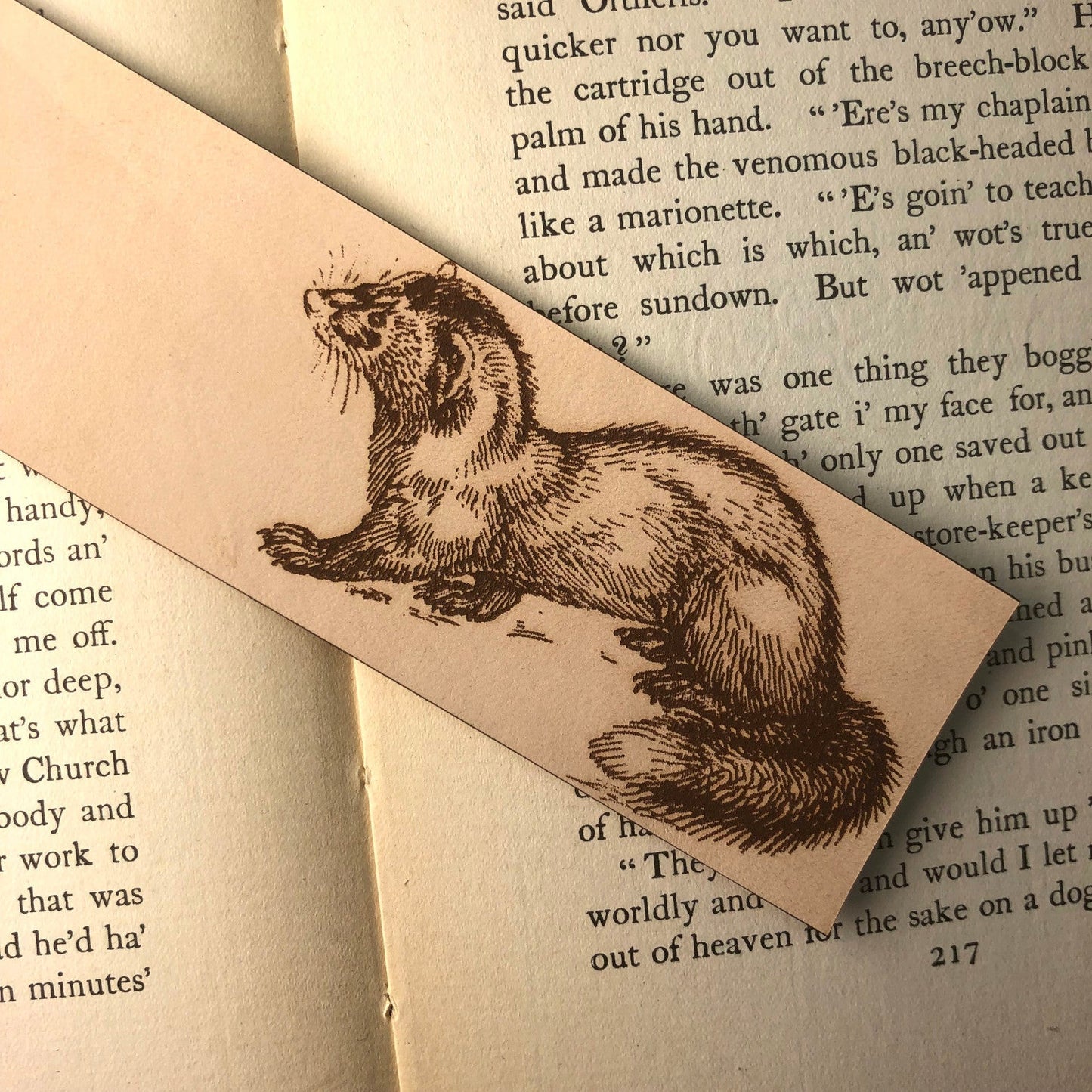 A close up of the rectangular leather bookmark with the art of a polecat engraved on it.