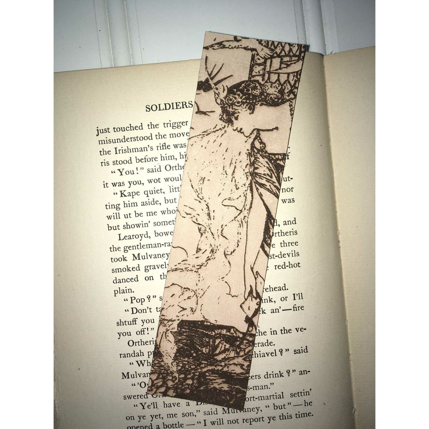 A rectangular leather bookmark with the art of a woman, probably a princess leaning out of a tower.