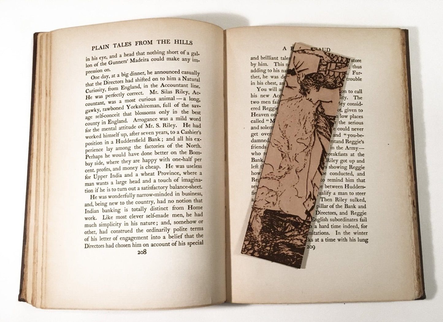 The leather bookmark of a princess leaning out of the tower resting on an antique book.