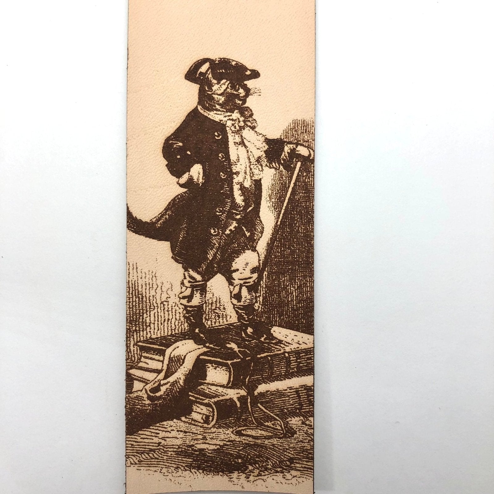 A close up of the puss in boots illustration engraved on the leather bookmark.