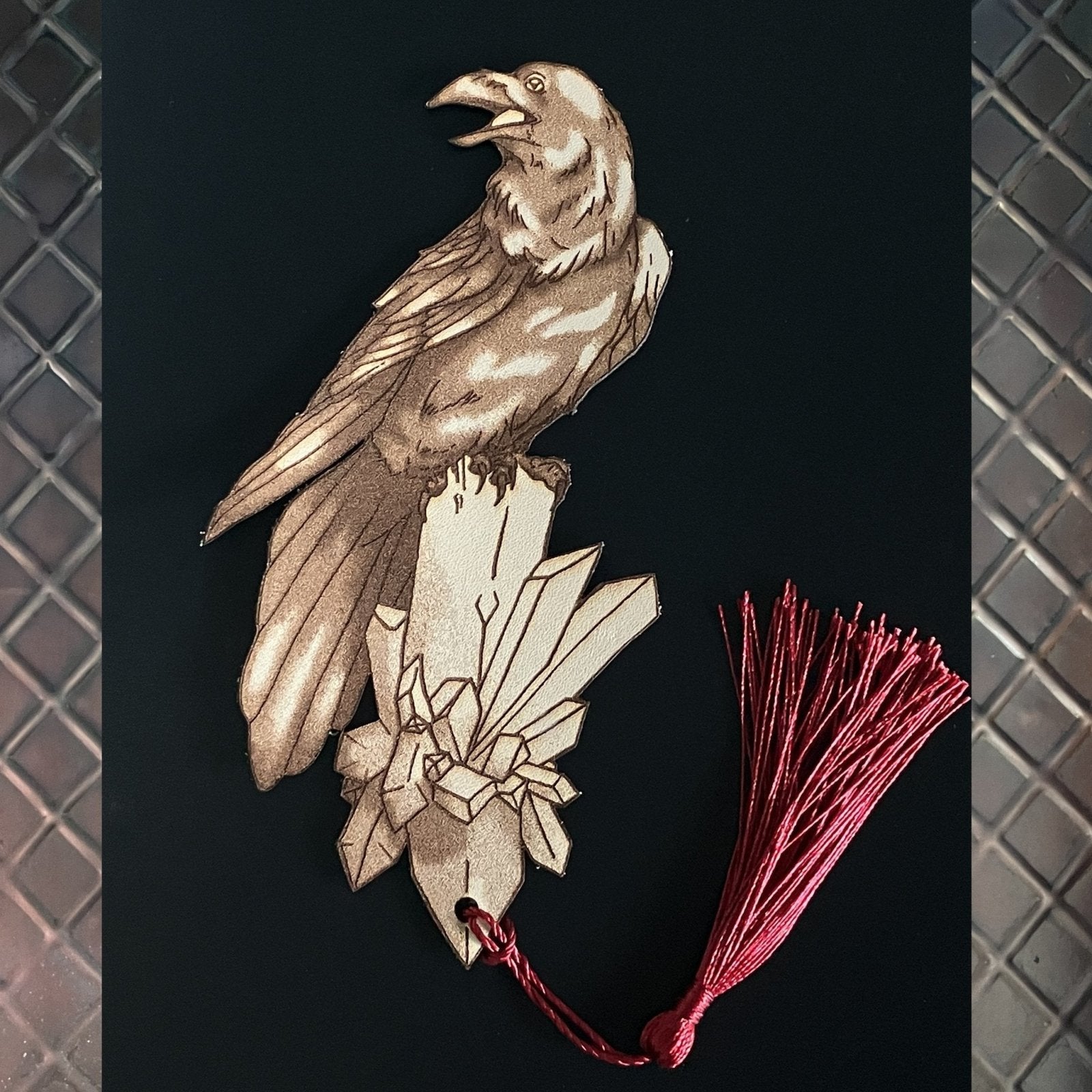 A raven shaped bookmark with a tassel. The raven's mouth is open. Raven Bookmark - Leather Bookmarks Raven King Crafts