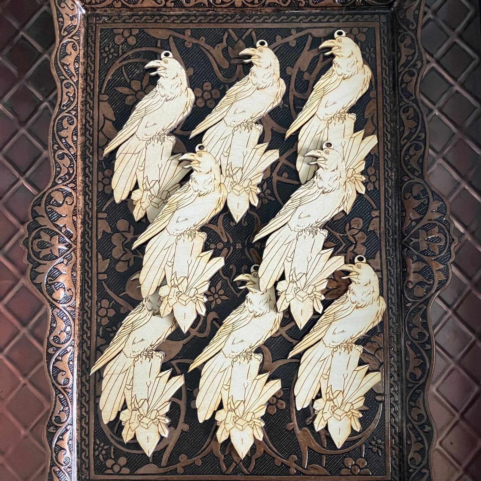 A photograph of 8 wooden raven shaped ornaments resting on a metal tray. Raven with a Crystal Shaped Wooden Ornaments Art & Craft Kits Raven King Crafts