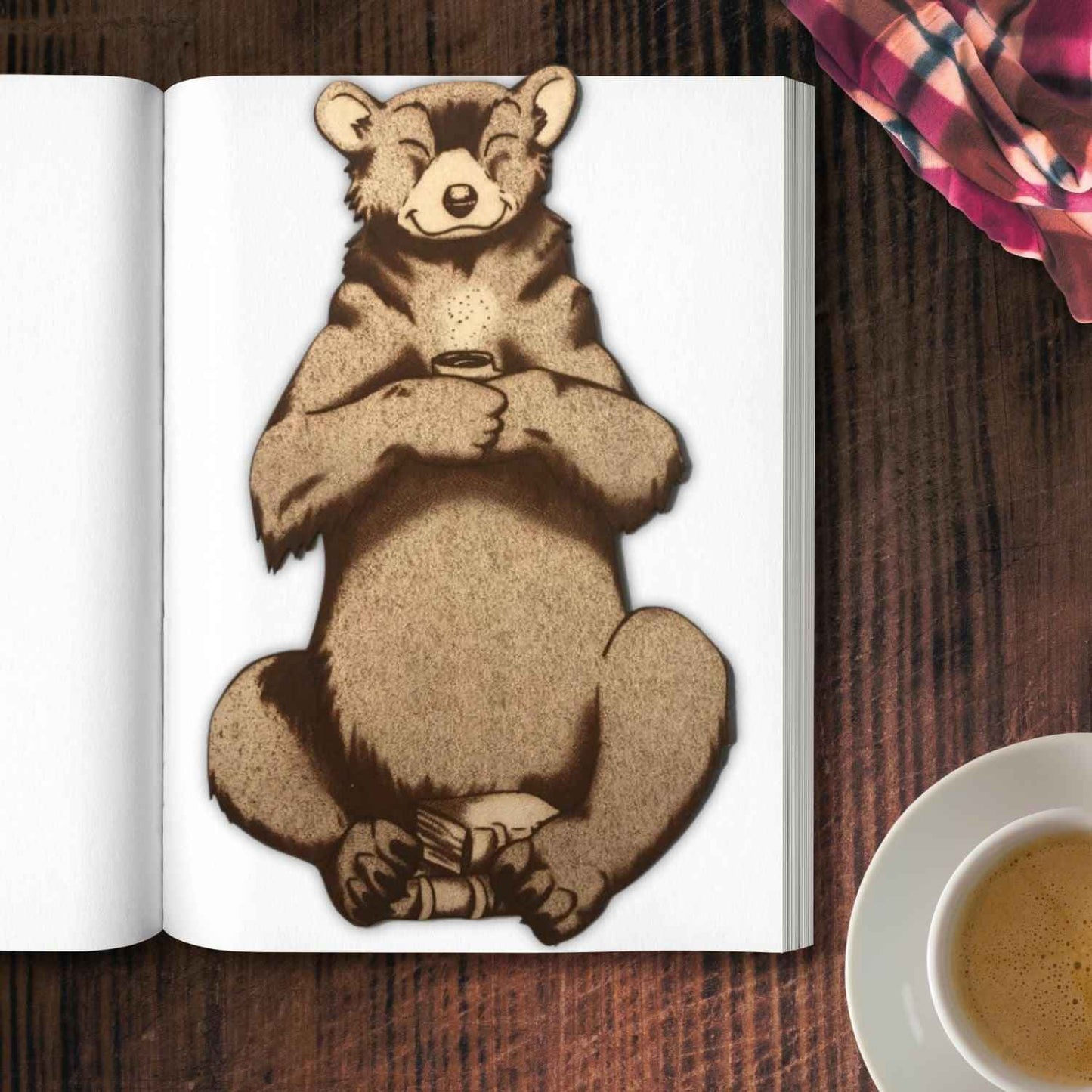 The leather bear bookmark where the bear is holding a cup and has a pile of books by it. Reading Bear with a Mug - Leather Bookmark Bookmarks Raven King Crafts