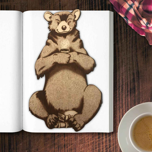 The leather bear bookmark where the bear is holding a cup and has a pile of books by it. Reading Bear with a Mug - Leather Bookmark Bookmarks Raven King Crafts