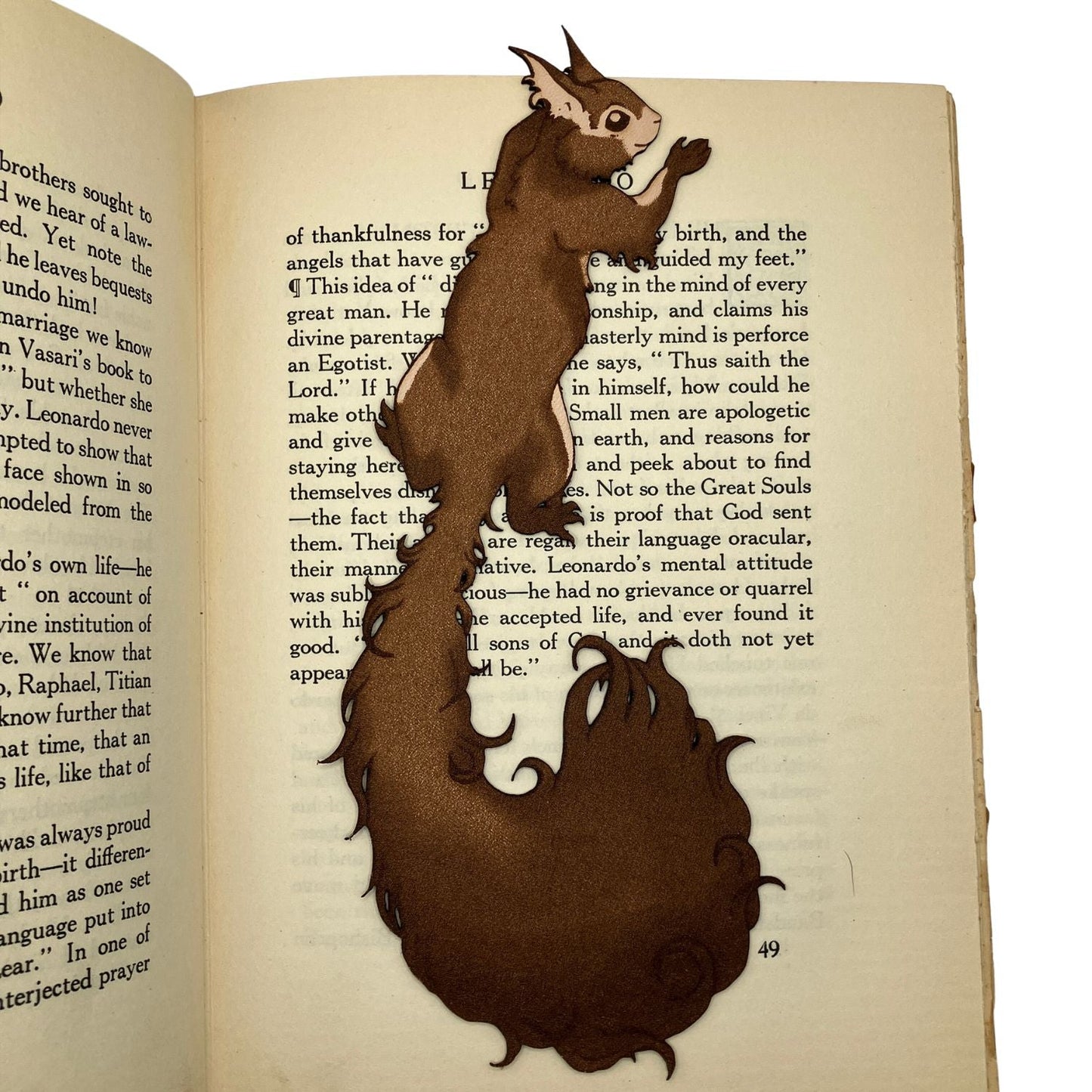 A photo of the red squirrel bookmark resting on the pages of an open book.