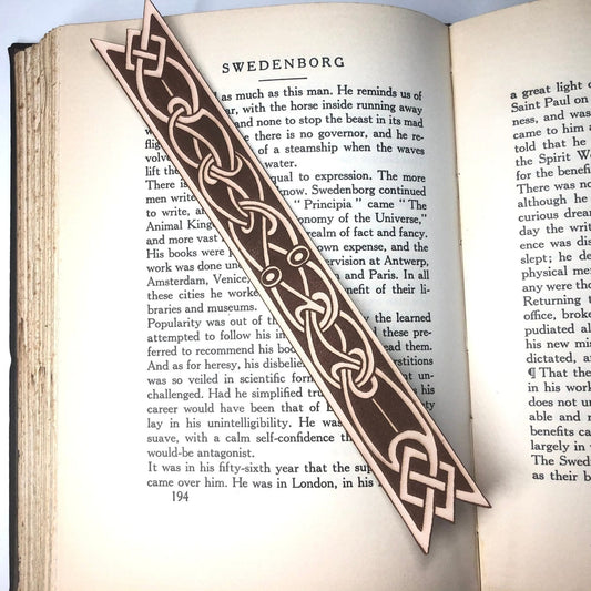 A long thin bookmark made from leather with the art of a Celtic knot on it.