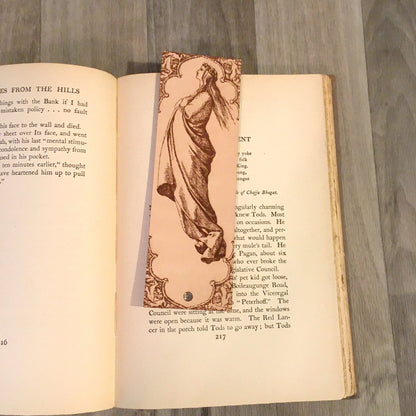 Leather bookmark with the ornate historical art of a woman wearing a robe on it.