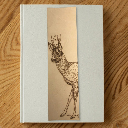 A photo of the roe deer bookmark resting on a white book. Roe Deer Bookmark - Leather Bookmarks Raven King Crafts