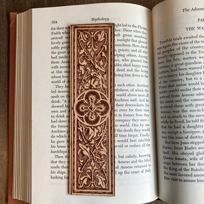 A leather rectangular bookmark with the art of a rounded cross at the center of it.