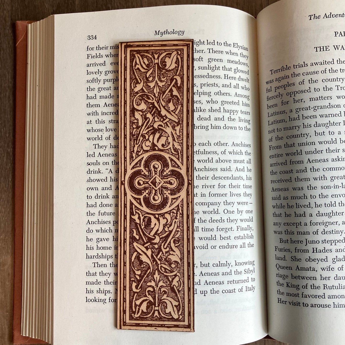 A photograph of historical rounded cross medallion leather bookmark resting on the pages of an open book. Rounded Cross Medallion Bookmark Bookmarks Raven King Crafts