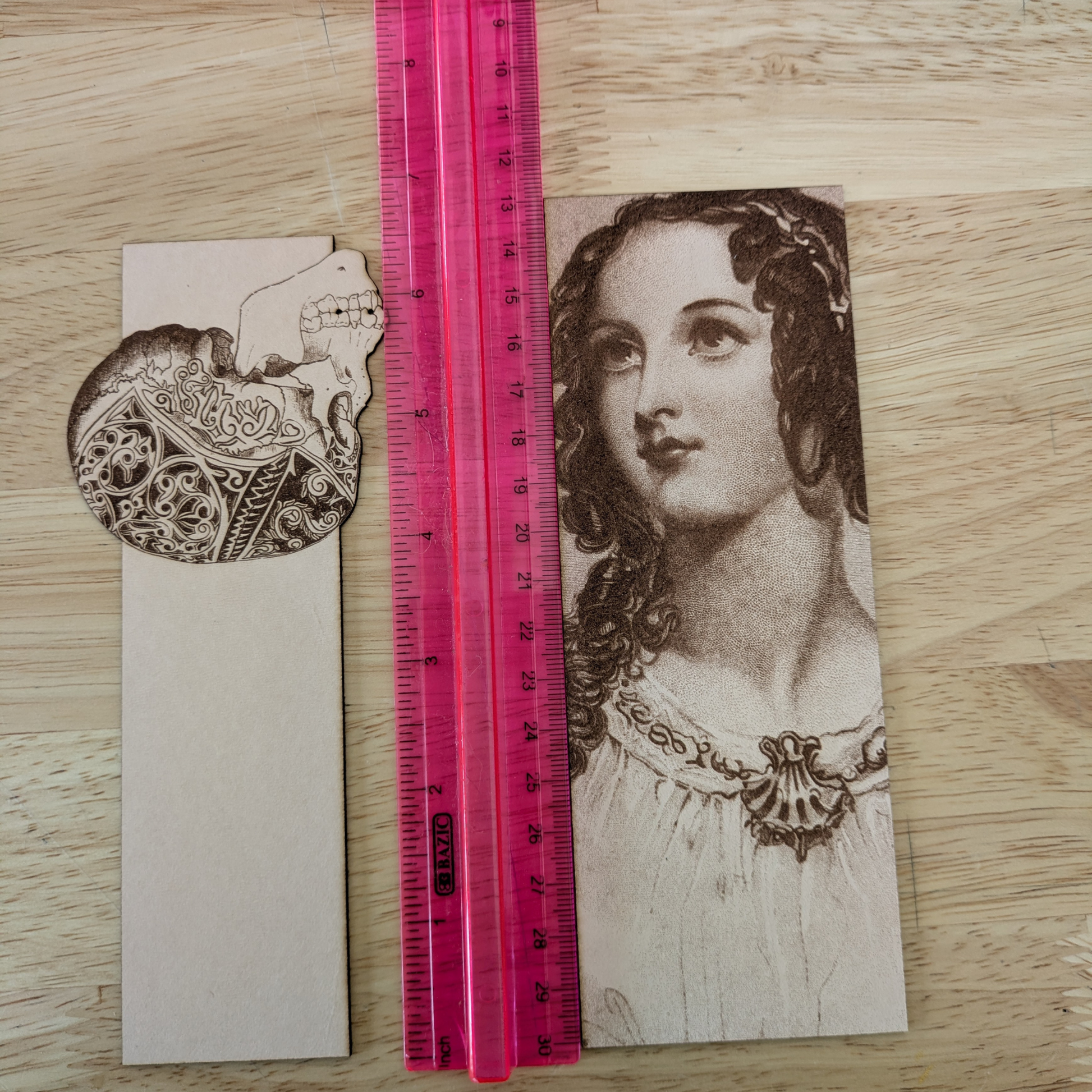 A photograph of a skull bookmark and a woman bookmark next to a ruler. 