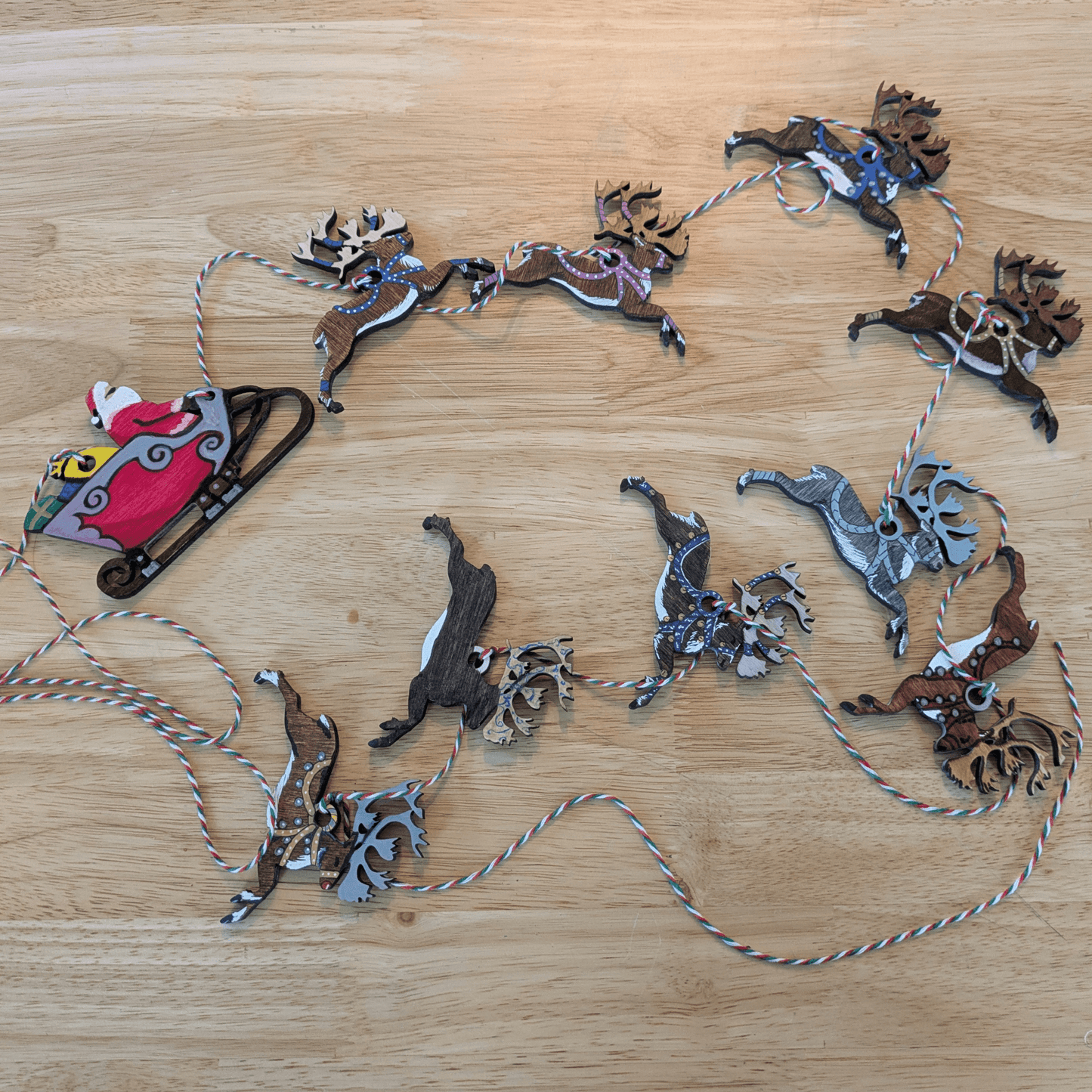 Examples of finished ornaments arranged with string for a Christmas garland. Santa and his reindeer ornament or garland blanks - 9 Deer, wooden Art & Craft Kits Raven King Crafts