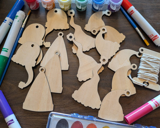 A photograph of the wooden Santa hat Christmas ornament blanks. Around them are markers and paints you can select. Santa Hat Ornament Kit - 15 Ornaments Ornament Raven King Crafts