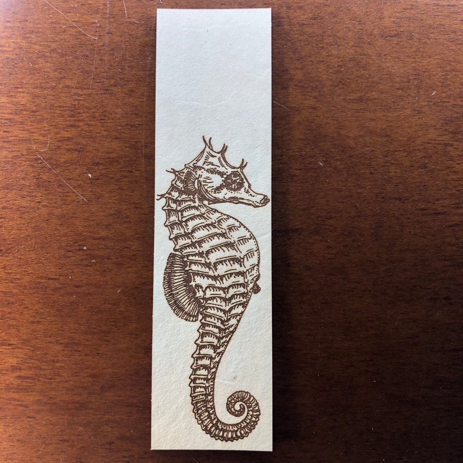 The seahorse leather bookmark on a wood background.