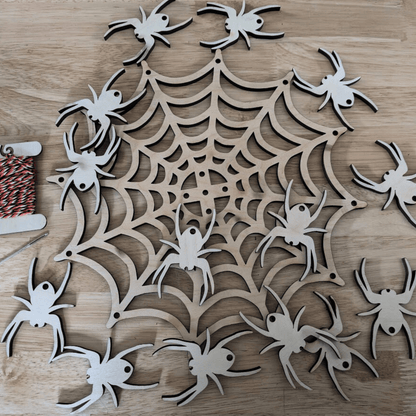 A photograph of the spider web mobile kit. It shows the Halloween themed string, metal needle, wooden spider web and 14 wooden spiders. Spider Web Mobile Kit Art & Craft Kits Raven King Crafts