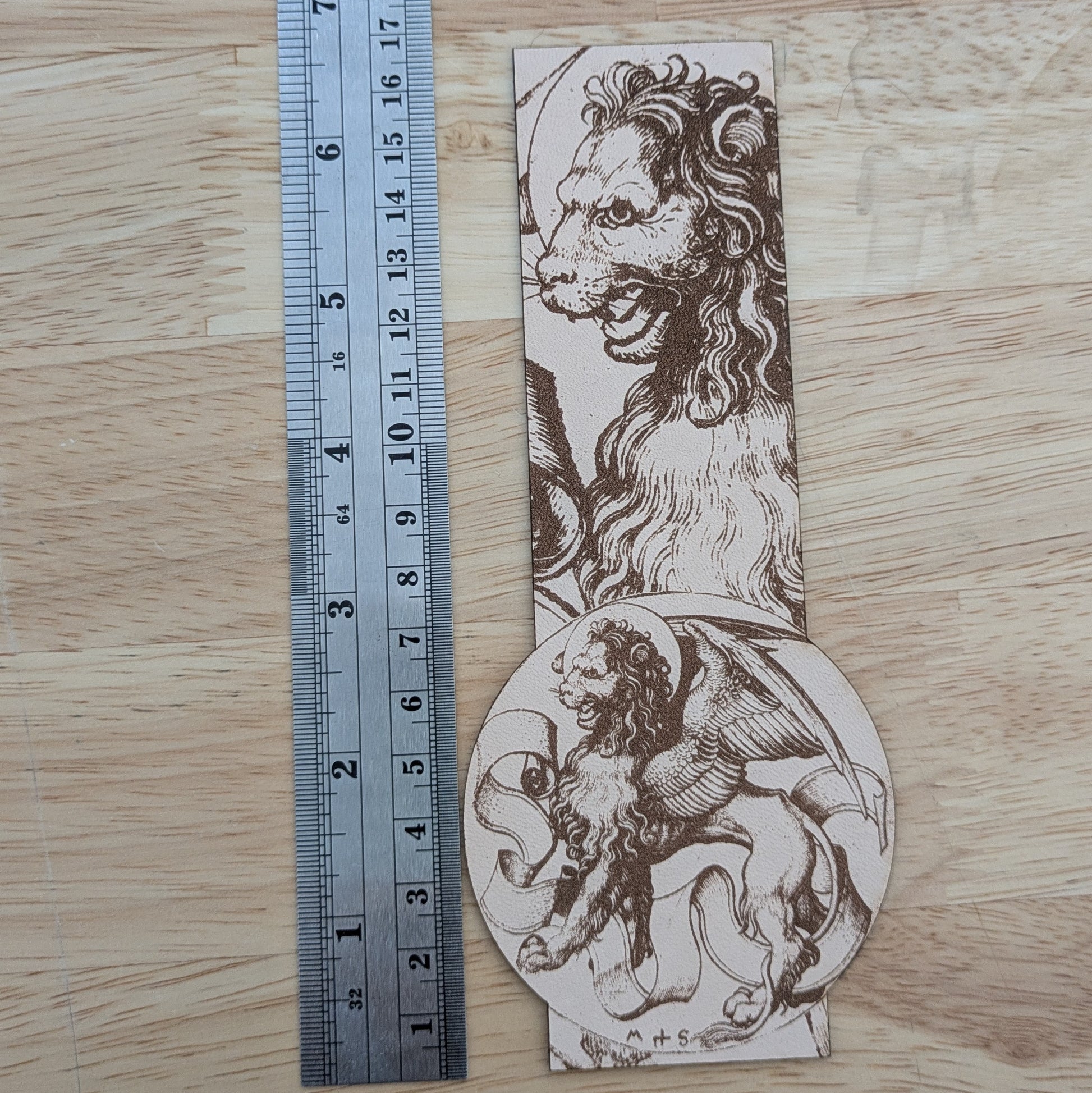 The winged lion bookmark next to a metal ruler for scale. 