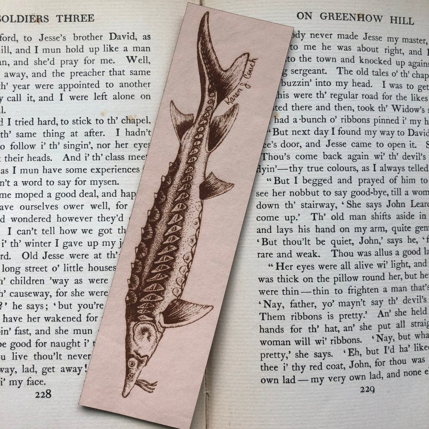 A photograph of a leather bookmark with a sturgeon fish engraved on it.