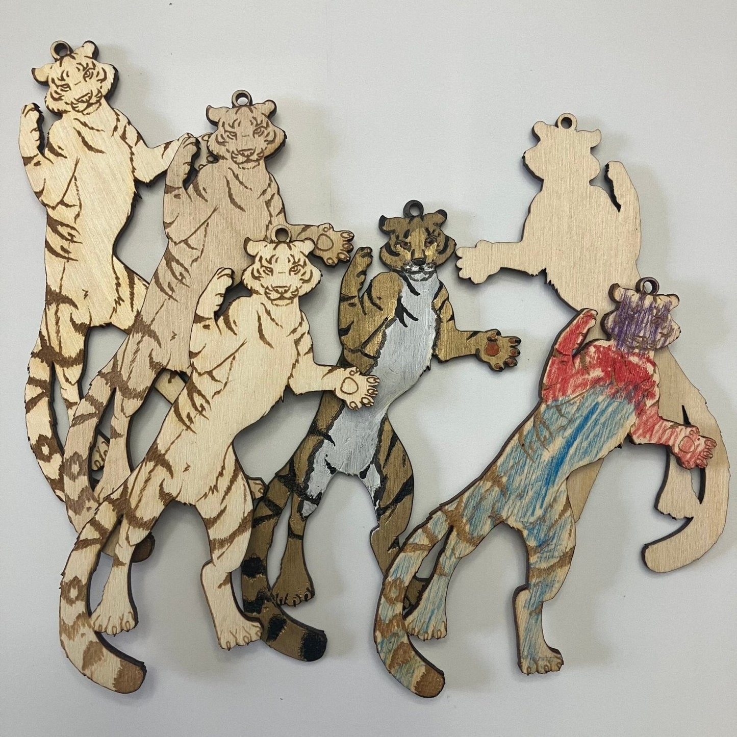 A pile of wooden tiger ornaments, with some finished and most blank. Tiger Shaped Wooden Ornaments Art & Craft Kits Raven King Crafts