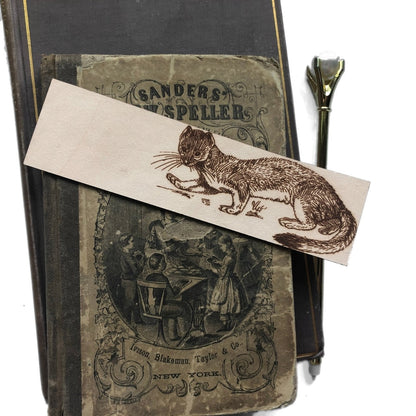 The leather weasel bookmark on top of some antique books. Weasel Bookmark Bookmarks Raven King Crafts