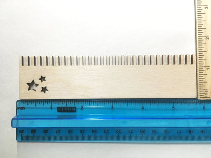 The weaving comb with stars next to a ruler for scale.