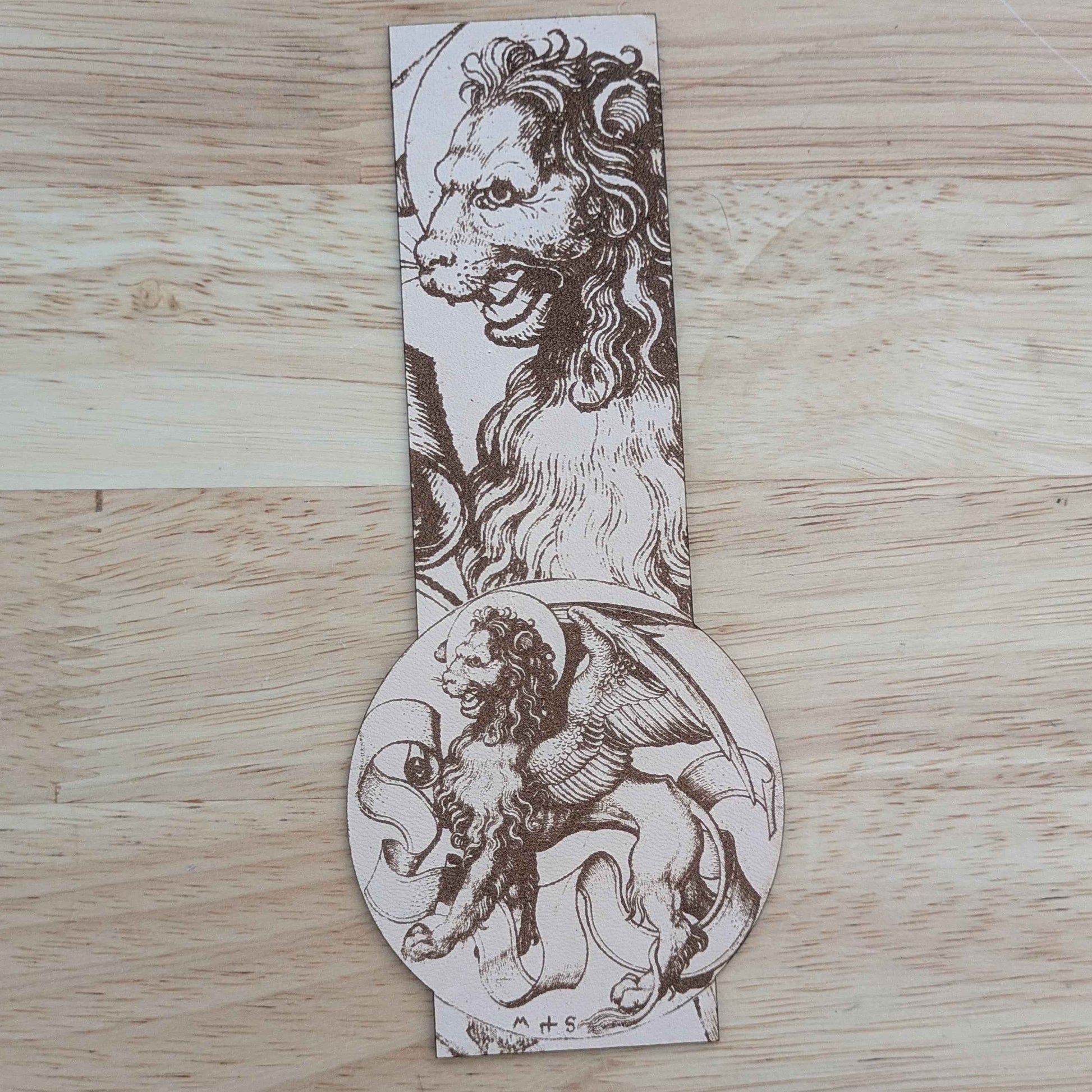 A photograph of a leather bookmark featuring the historical art of a winged lion beast.